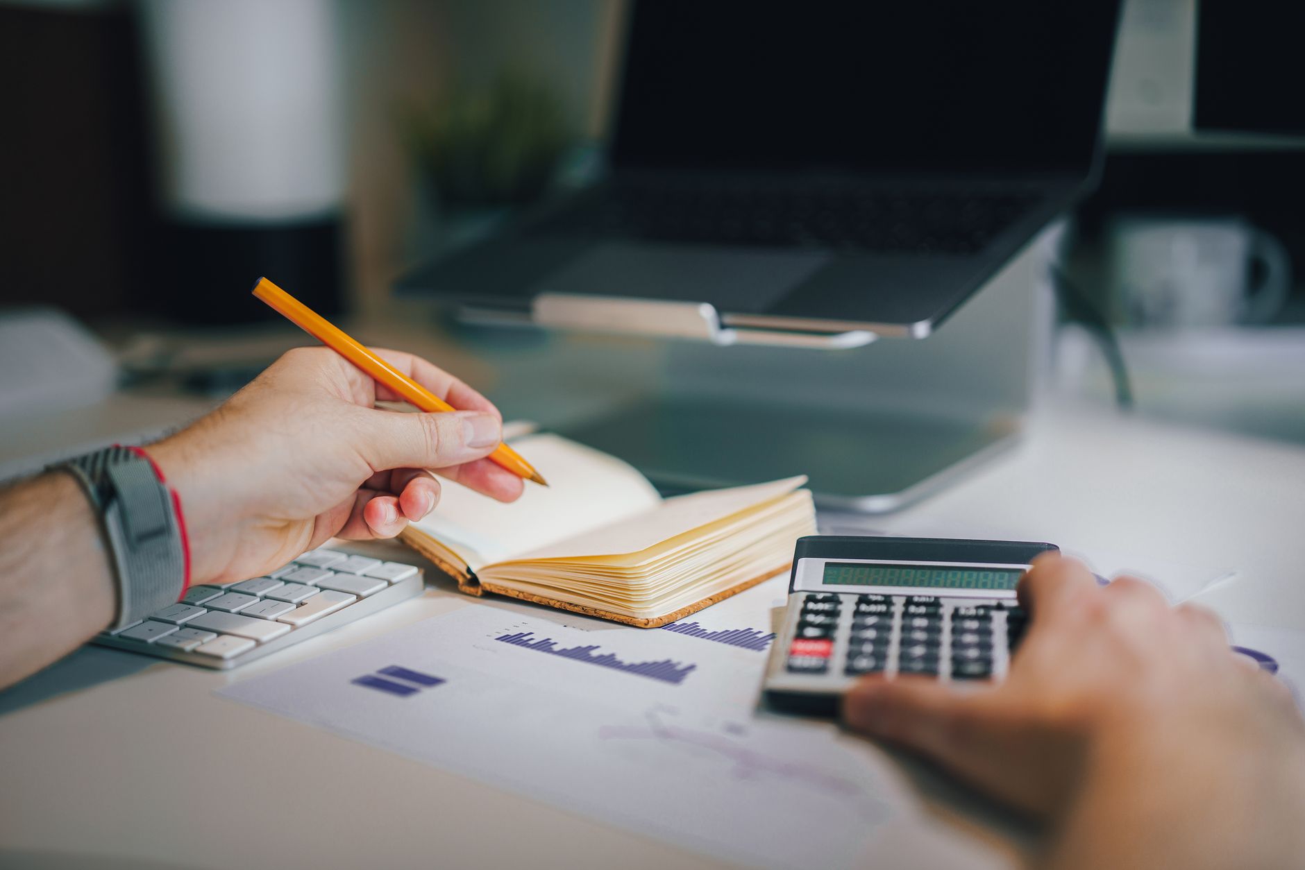 Hands with a calculator, notepad and laptop on a desk — reviewing remote healthcare attorney pay